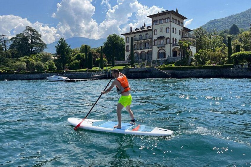 A person paddleboarding on a calm lake with a historic building in the background. 3