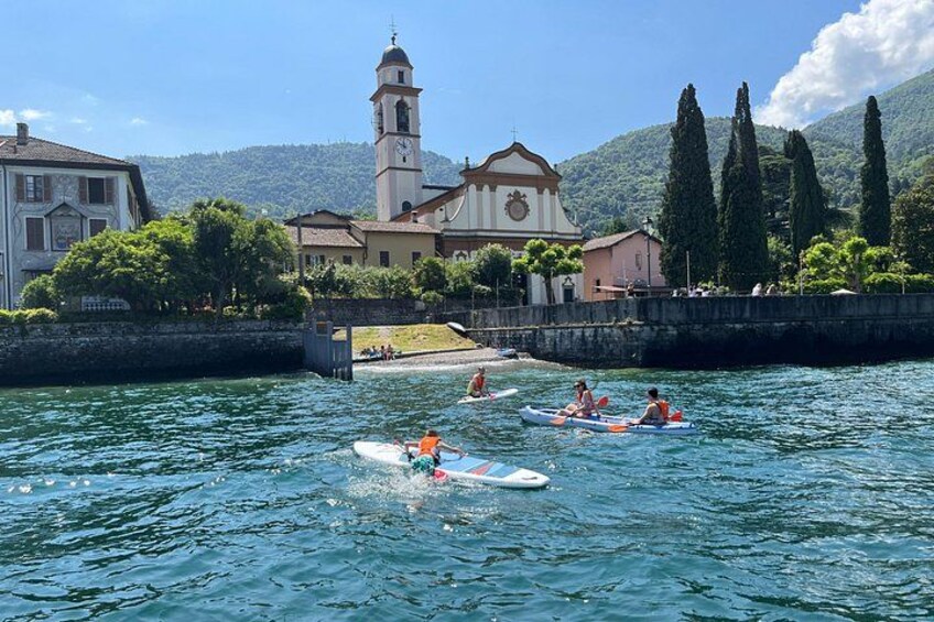 People kayaking on a lake with buildings and a church in the background. 5