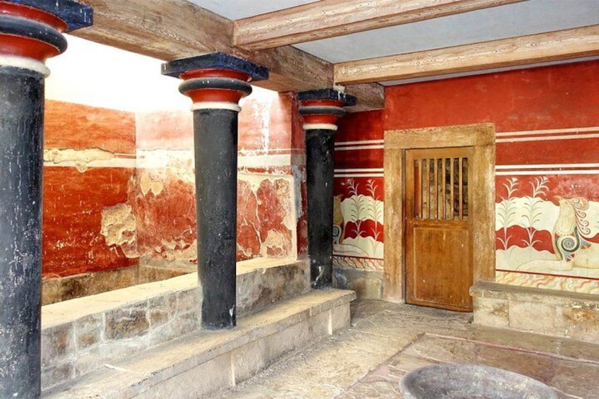 Una habitación con paredes rojas, columnas negras y una puerta de madera. 3