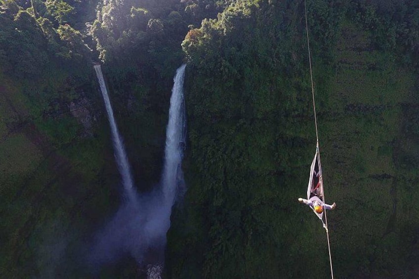 Eine Person macht Bungeesprung von einer hohen Klippe, darunter ein Wasserfall. 5