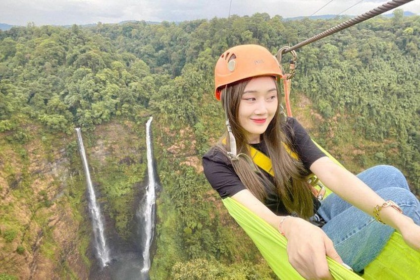 Eine Person auf einer Zipline, im Hintergrund Wasserfälle. 1