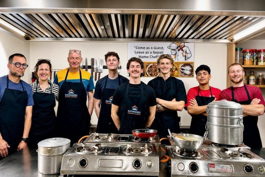A group of people standing in a kitchen with cooking equipment. 3