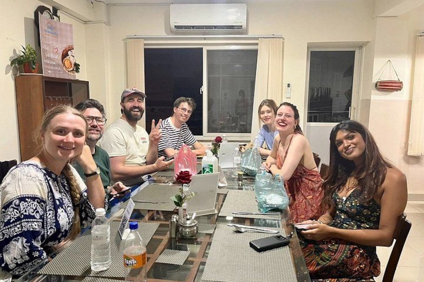 A group of people sitting around a table with drinks and a laptop. 2