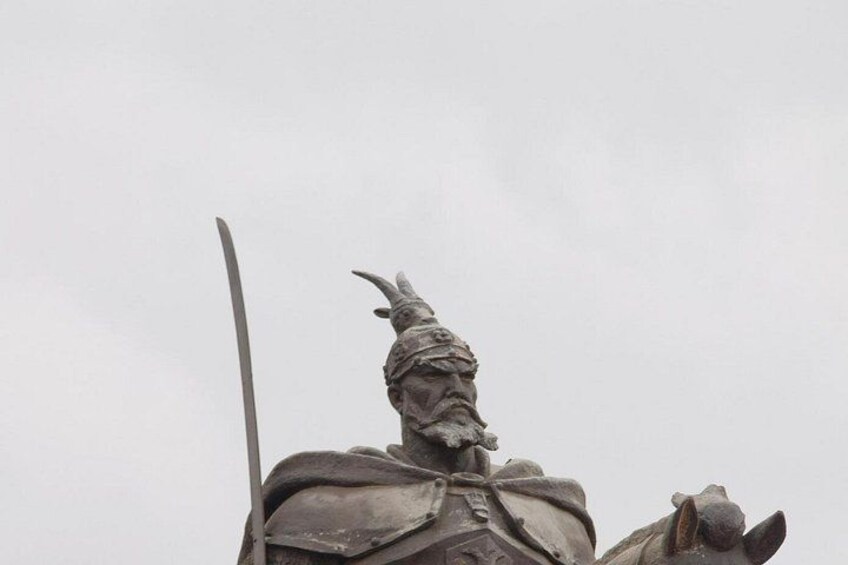 A statue of a warrior holding a sword, wearing armor, and mounted on a horse. 2