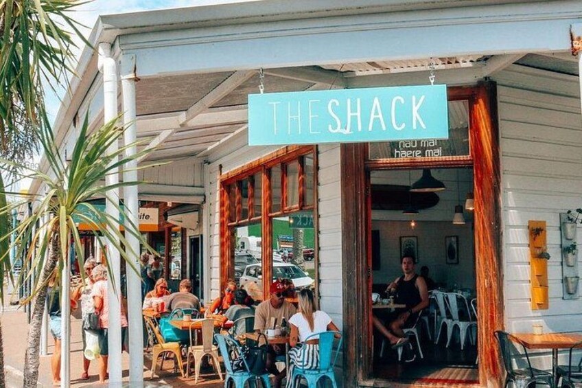 A coastal cafe named 'The Shack' with outdoor seating and a view of the sea. 3