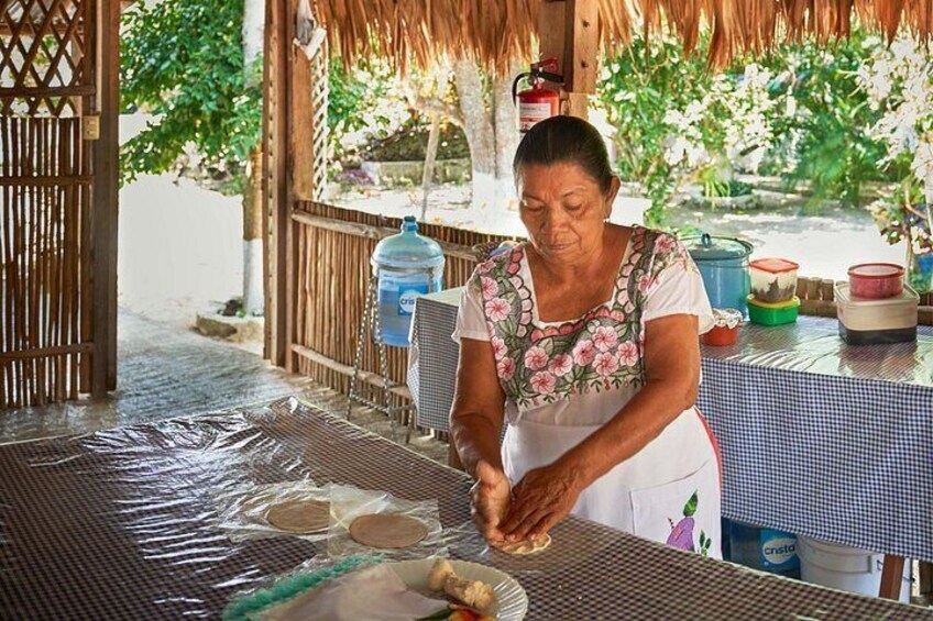 Una persona preparando comida al aire libre, con una mesa cubierta con plástico, utensilios de cocina y recipientes. 3