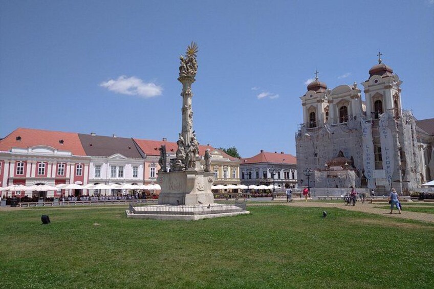 A statue in a square, a church with domes, and a building with a red roof. 5