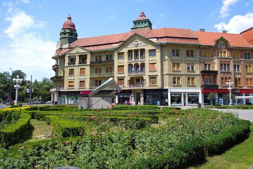 A historic building with a red roof, a tower, and a well-maintained garden with hedges and flowers. 3