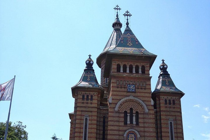A historic building with a clock tower, ornate brickwork, and a flag. 2
