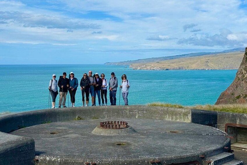 Un grupo de personas sobre una plataforma de concreto, con vista a una masa de agua y un litoral rocoso al fondo. 5