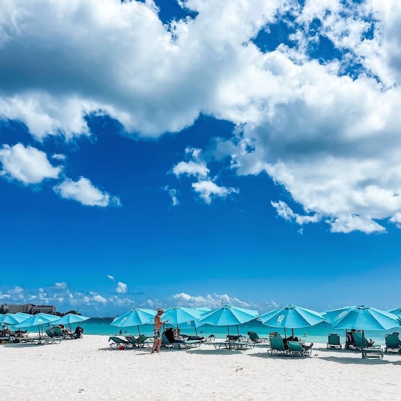 En strand med turkis parasoller og liggestole under en klar blå himmel. 5