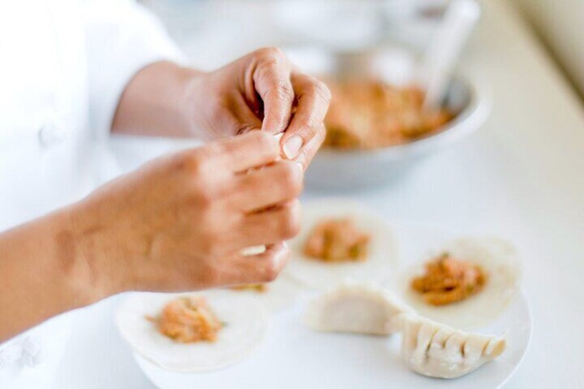Hands preparing dumplings on a plate. 3