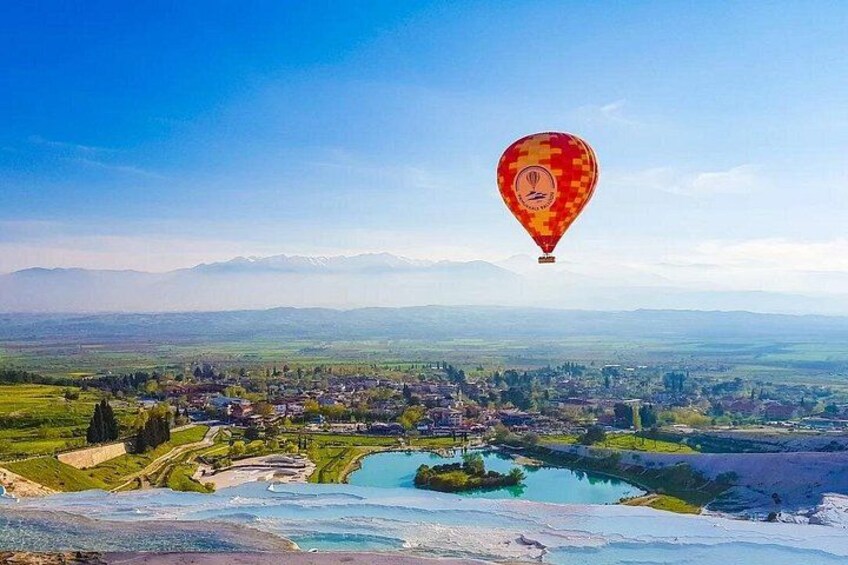 Un globo aerostático sobre un pueblo con un río y montañas al fondo. 4