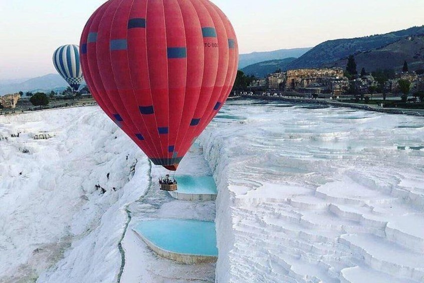 Un globo aerostático rojo sobre un paisaje helado con piscinas en terrazas. 2