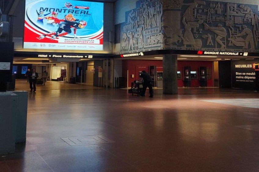 Un espacio interior amplio con un anuncio digital grande de Montreal, un banco y una tienda de muebles. 3