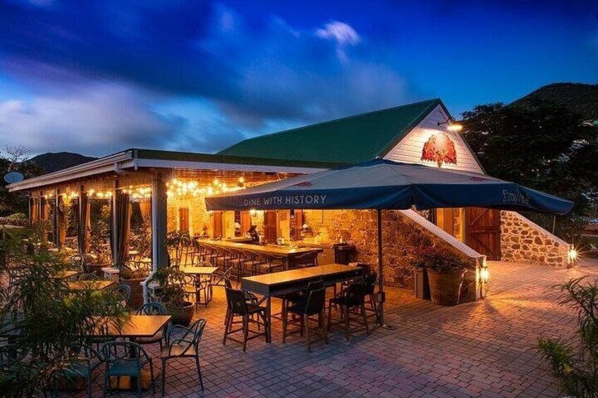 An outdoor dining area with tables and chairs, a covered section, and a sign that reads 'Dine with History.' 5
