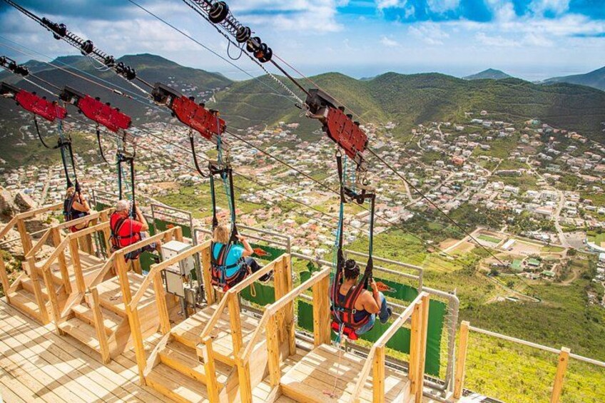 A cable car system with passengers, overlooking a town and mountains. 4