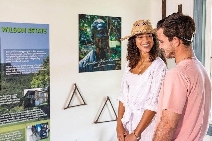 A couple standing in front of a wall with a poster of a man and a landscape. 2