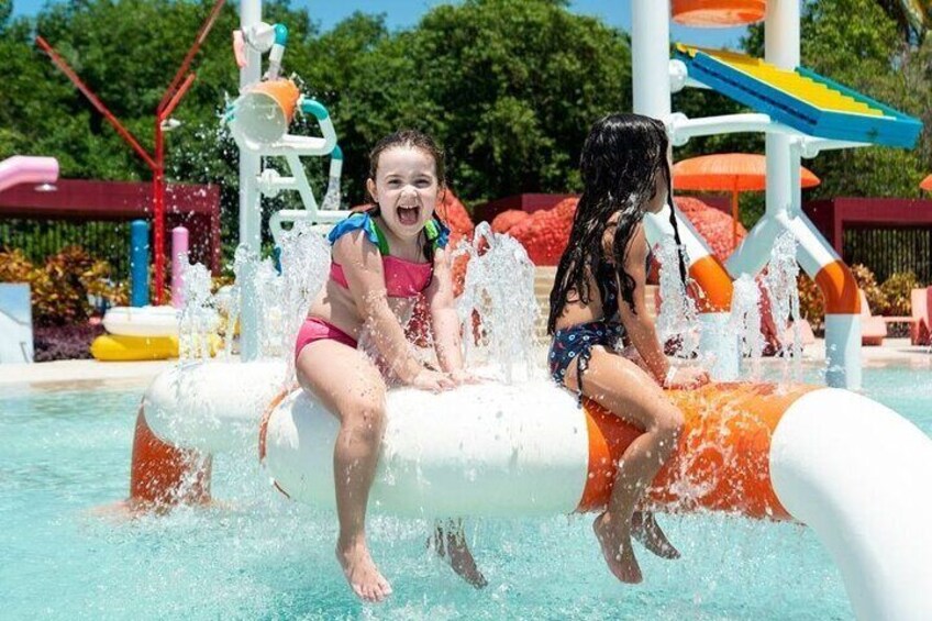 Two children playing in a water park, sitting on a water slide. 3