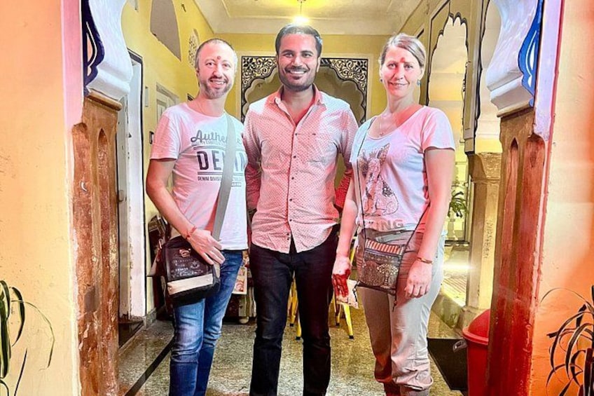 Three people standing in a hallway with ornate architectural details. 2