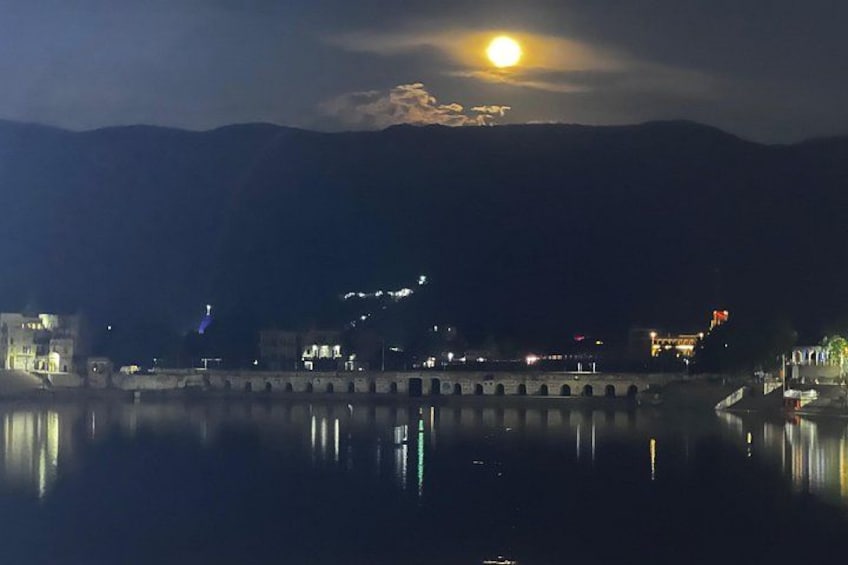 A moonlit night over a river with a bridge and buildings reflecting on the water. 3