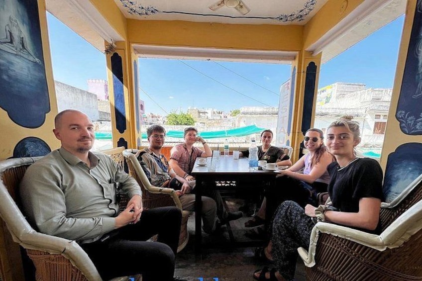 A group of people seated at a table inside a building with large windows. 4
