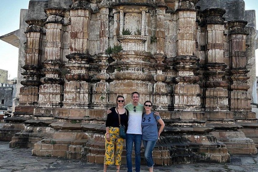 A group of people standing in front of an ancient stone structure with intricate carvings and columns. 5