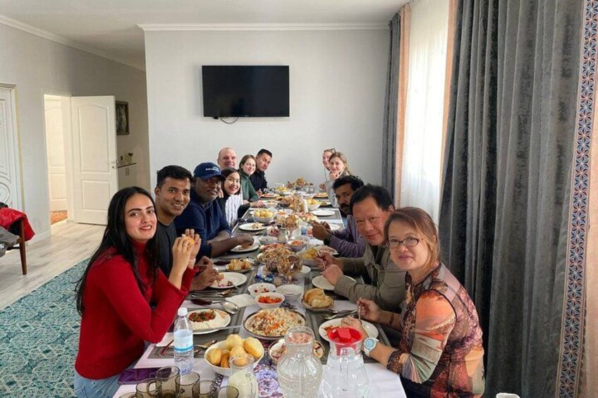 Un groupe de personnes est assis autour d’une longue table à manger, devant divers plats. 3