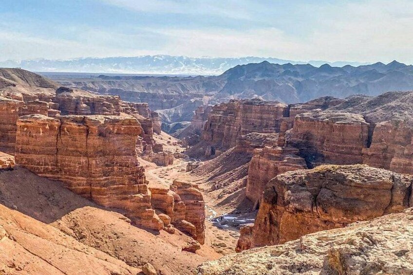 A canyon with layered rock formations and distant mountains. 3