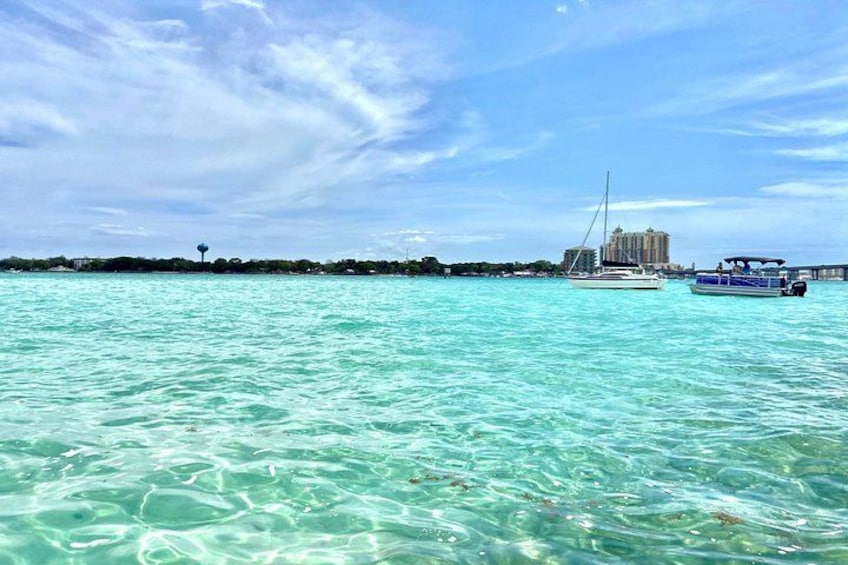 A clear turquoise sea, a sailboat, and a distant building. 4