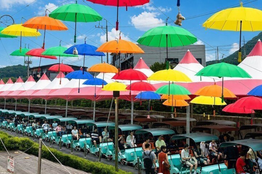 A row of colorful umbrellas and green chairs under a clear sky. 5