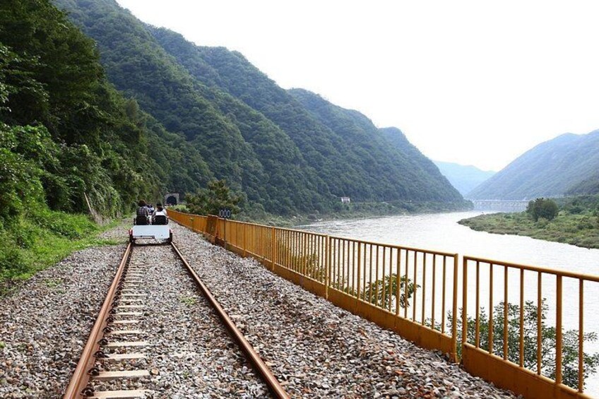 A train on tracks with a river and mountains in the background. 5