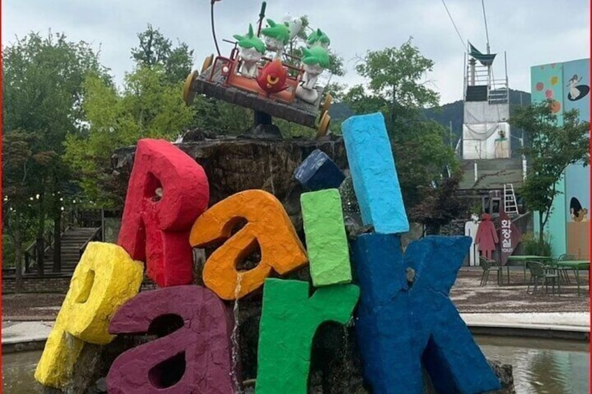 Colorful letters spelling 'Park' on a tree trunk, with a small vehicle on top. 2