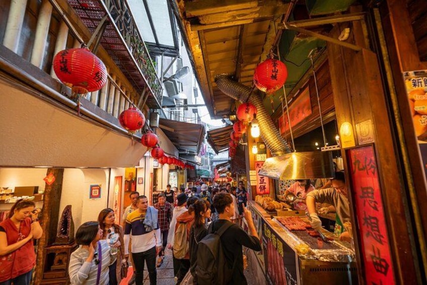 A bustling street market with red lanterns, food stalls, and people shopping. 2