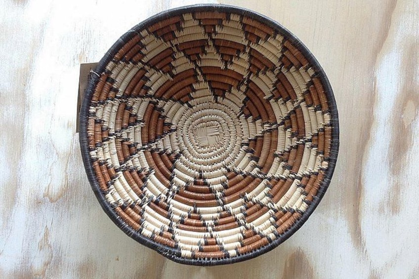 A circular woven basket with a spiral pattern, placed on a wooden surface. 2
