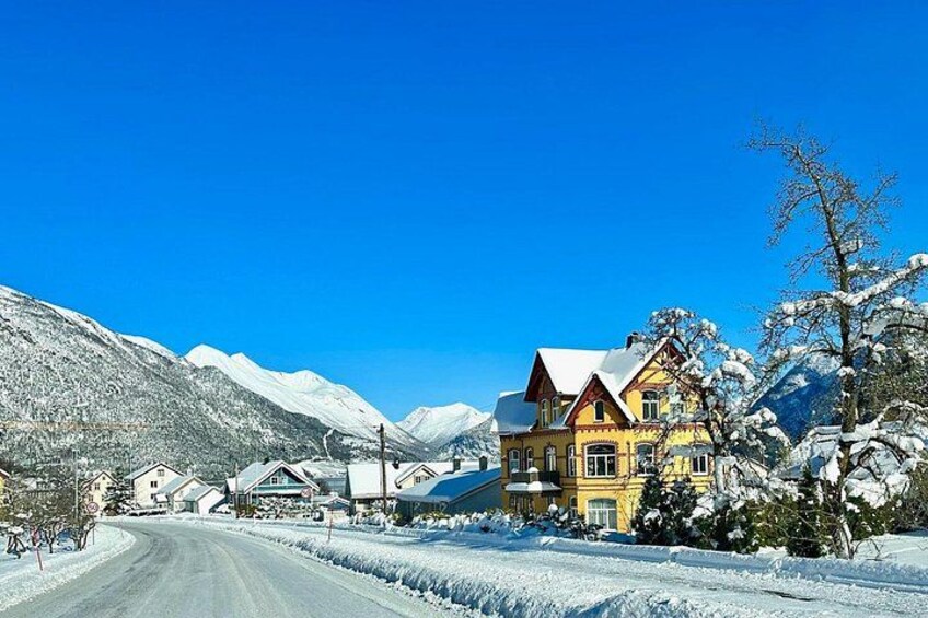 A snow-covered mountain road with houses and a large yellow building. 5