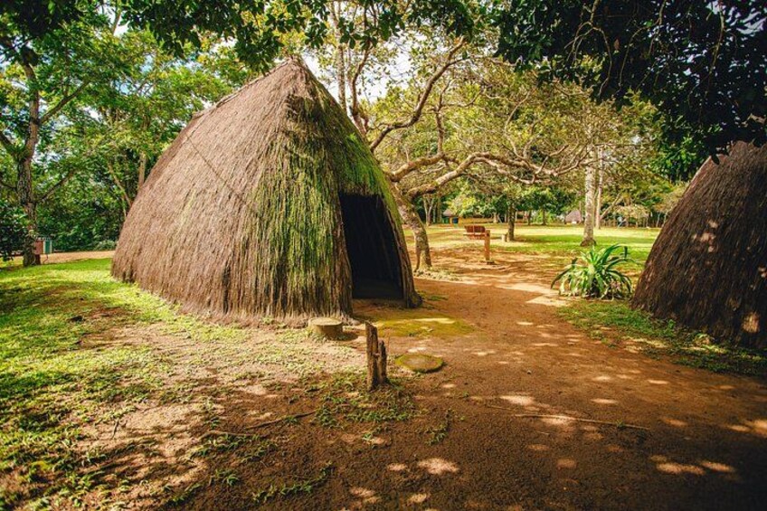 A thatched hut in a natural setting with a dirt path leading to it. 3