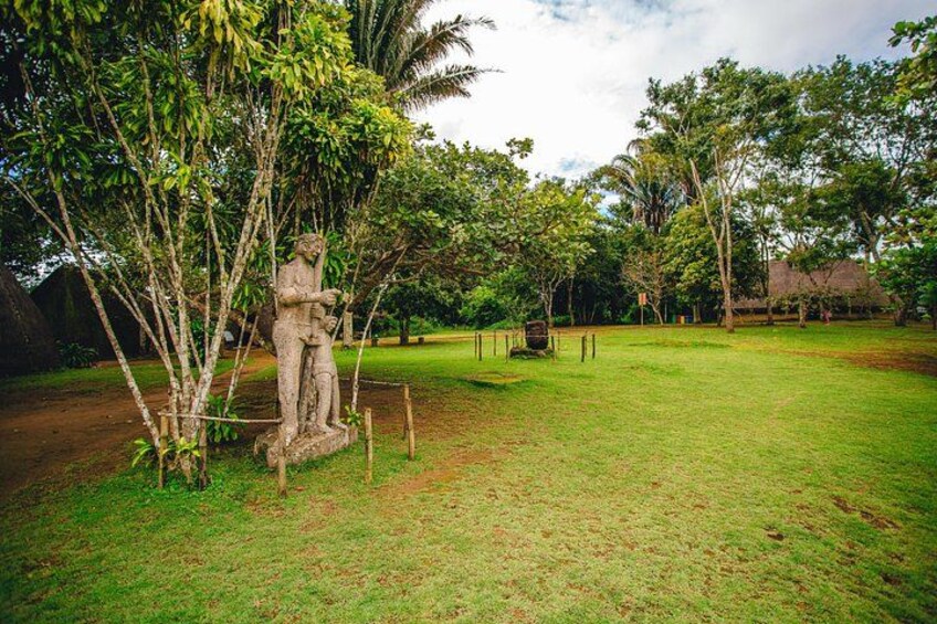 A statue in a grassy area with trees and a fence. 4