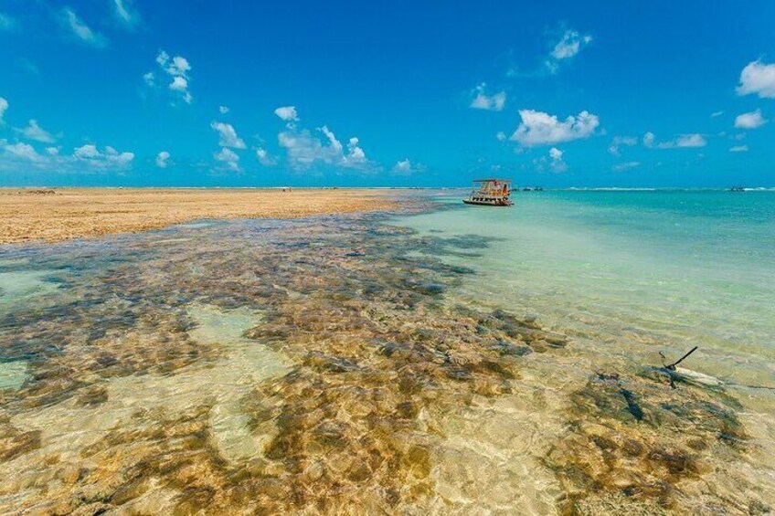 A clear beach with shallow water, a boat, and a distant shoreline. 3