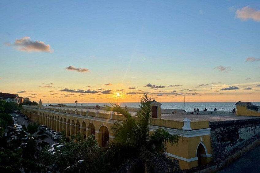 A coastal sunset with a bridge, palm trees, and a calm sea. 5