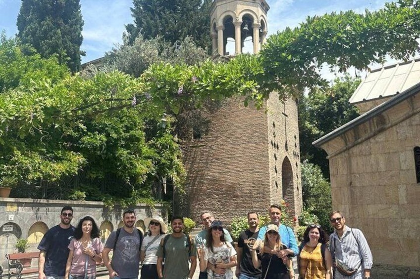 A group of people standing in front of a historic building with a bell tower. 5