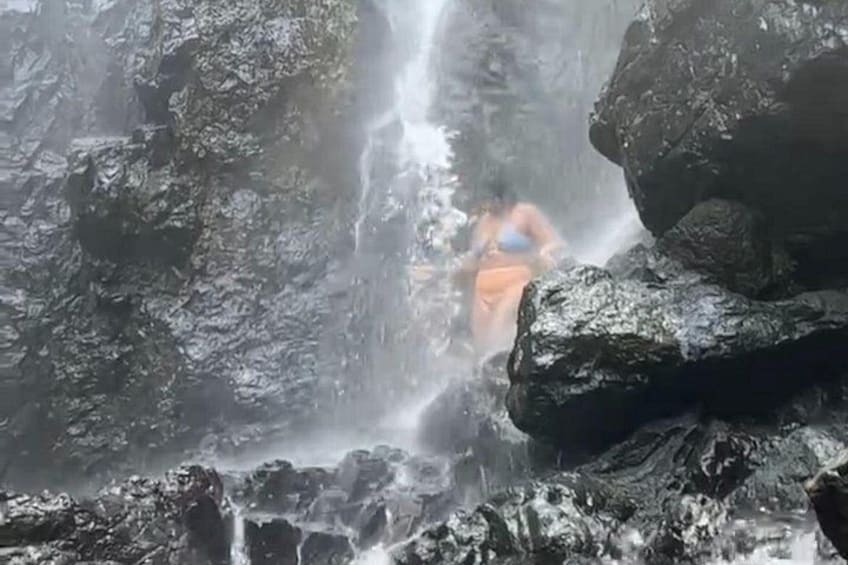 A waterfall with rocks and a person in the water. 3