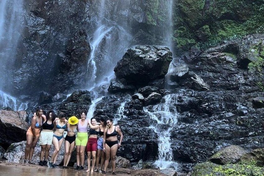 A group of people standing by a waterfall in a rocky area. 5