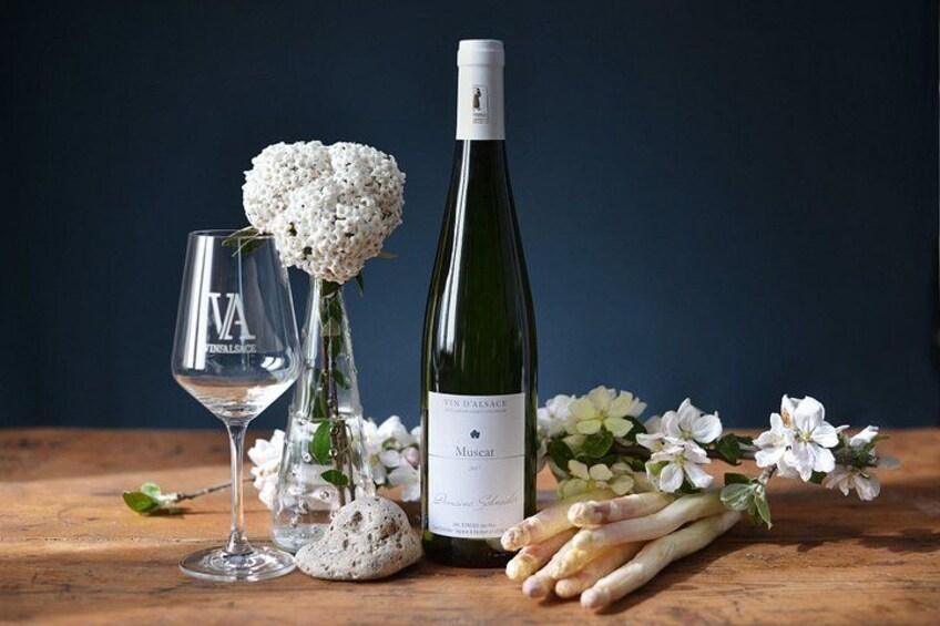 Une bouteille de vin, deux verres à vin et un bouquet d’asperges sur une table en bois, agrémentée de fleurs blanches. 2