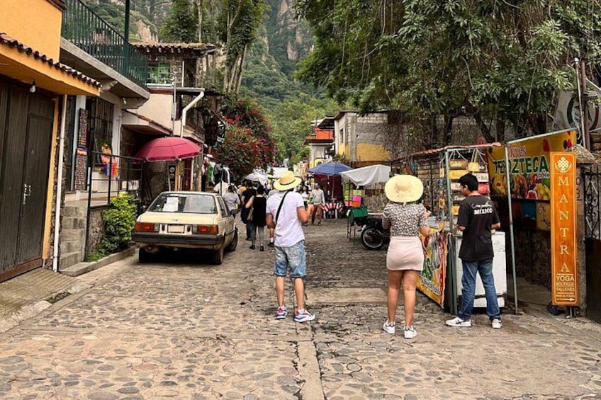 A cobblestone street with people, a parked car, and a yoga store. 5