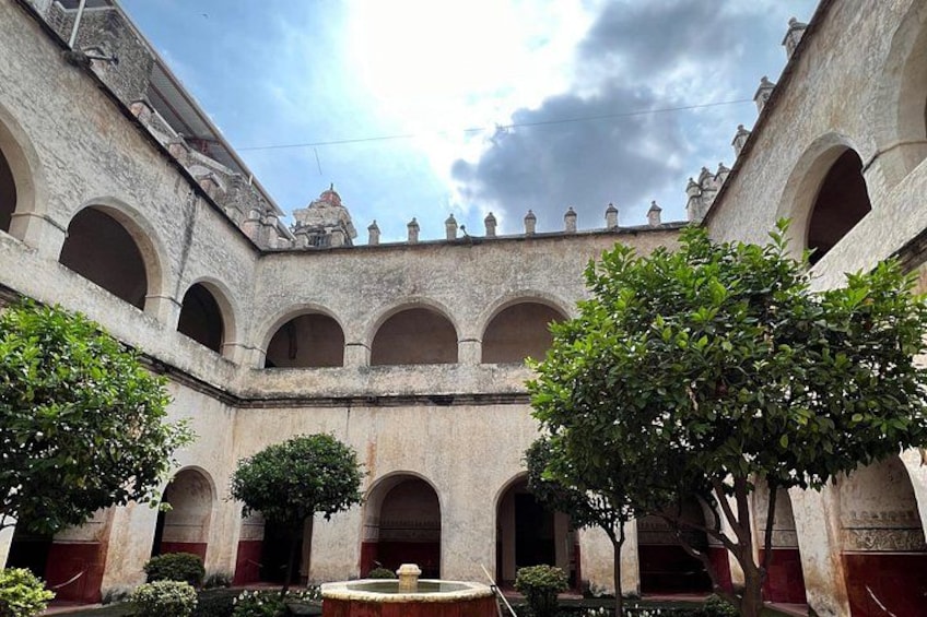 A courtyard with arches, a fountain, and trees. 2