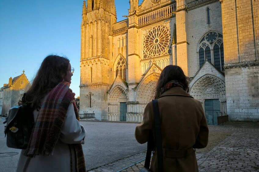Two people standing in front of a cathedral with a large rose window and Gothic architecture. 3