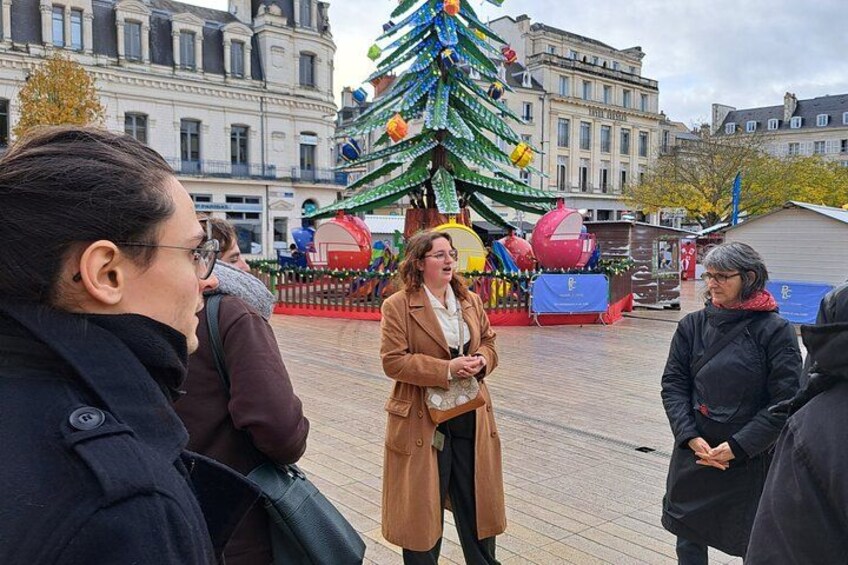 En grupp människor som står på ett offentligt torg med ett julpyntat julgran i bakgrunden. 2
