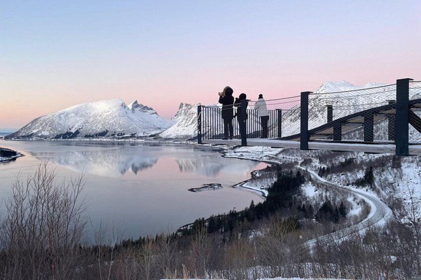 A frozen lake with a bridge and snow-covered mountains in the background. 3