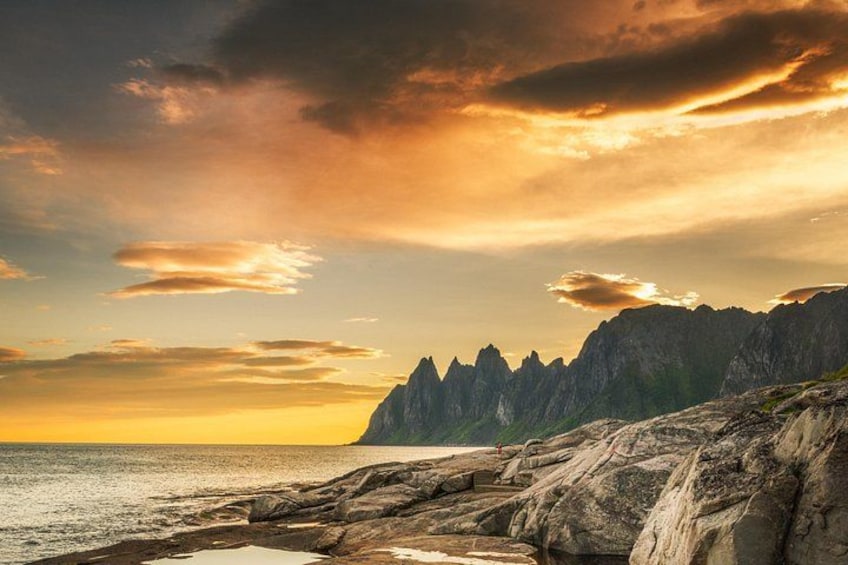 A coastal landscape with rocky terrain and a mountain range in the background. 1